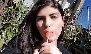 showing off outdoors sucking a lollipop
